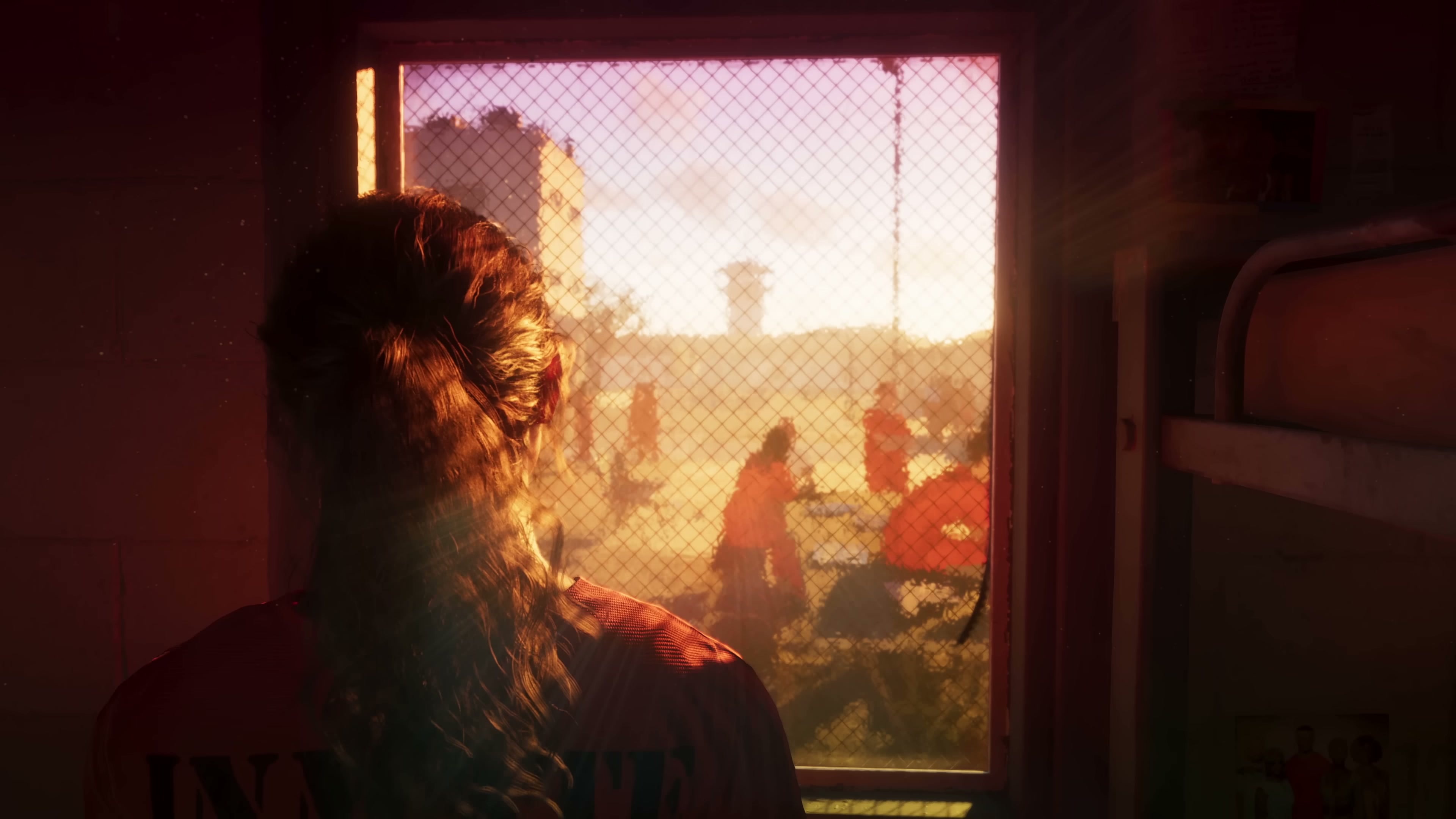 Lucia in an orange INMATE shirt looking out through a chain-link window into a prison yard.