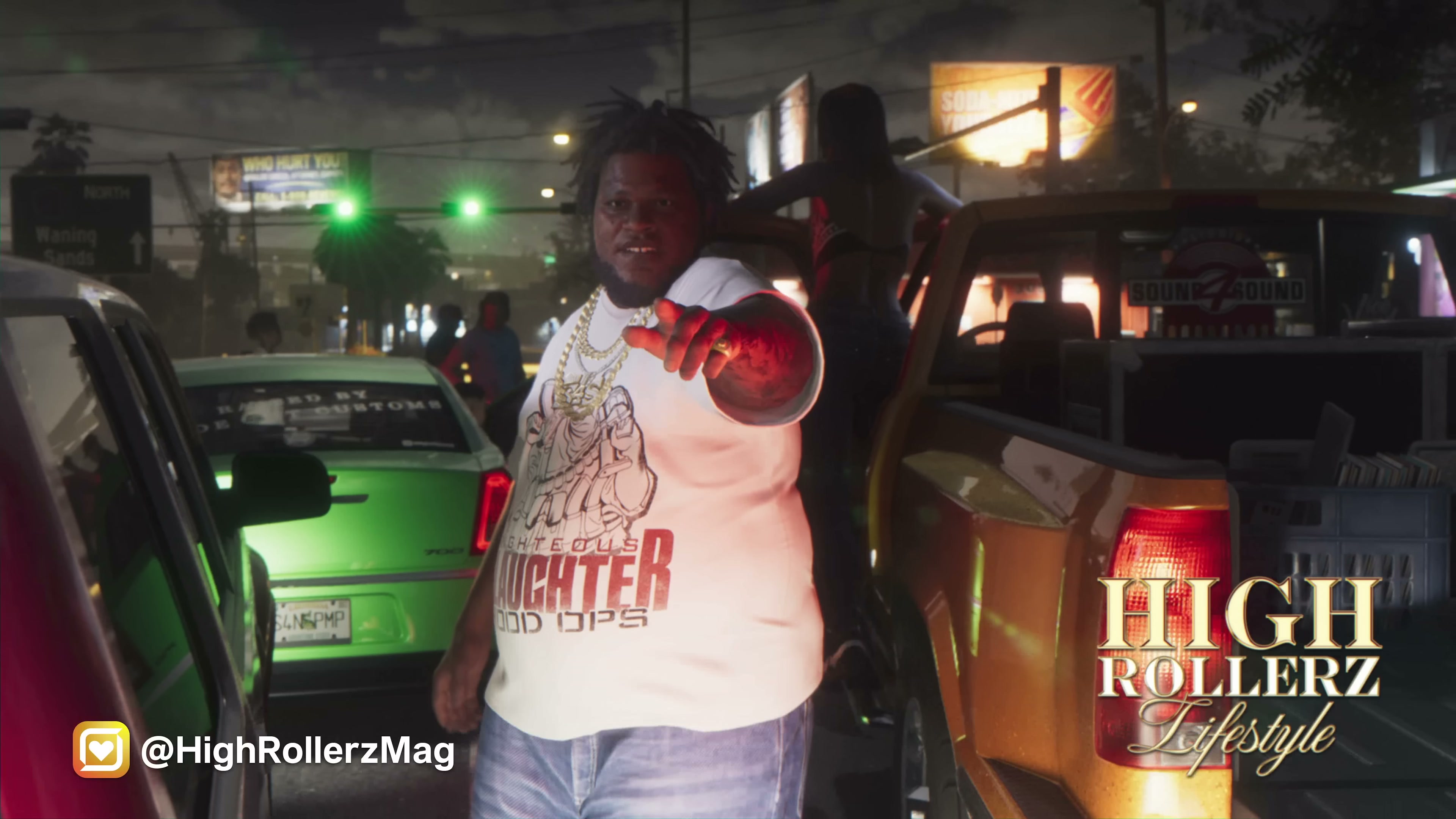 Heavyset man in white t-shirt and gold chain on a Vice City street at night with billboards behind him