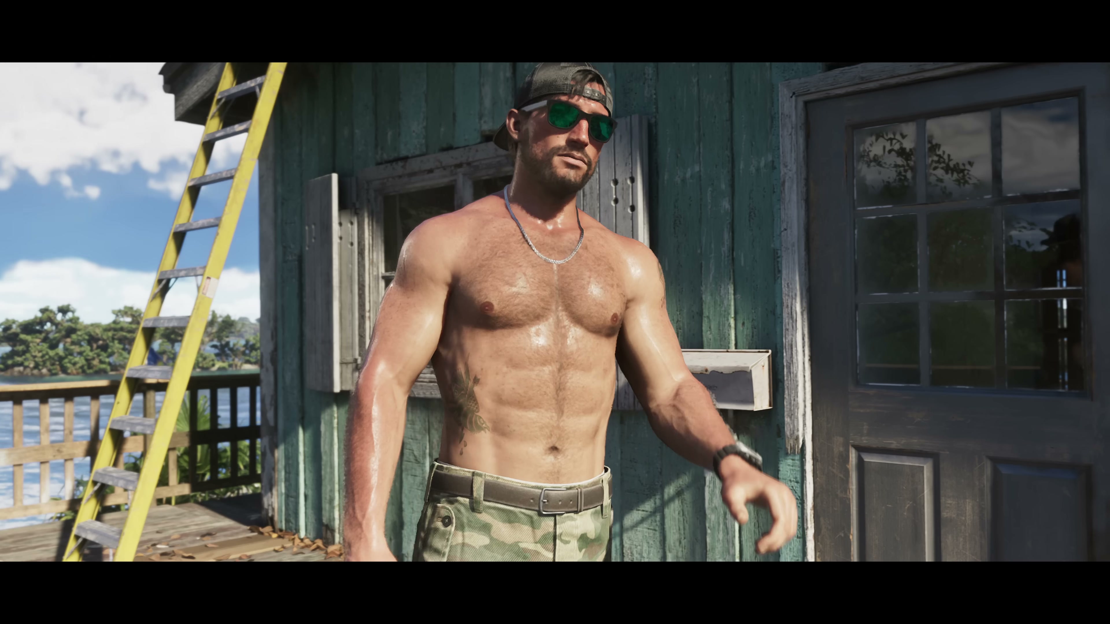 Shirtless man in camo cap and pants standing in front of green cabin in the Keys