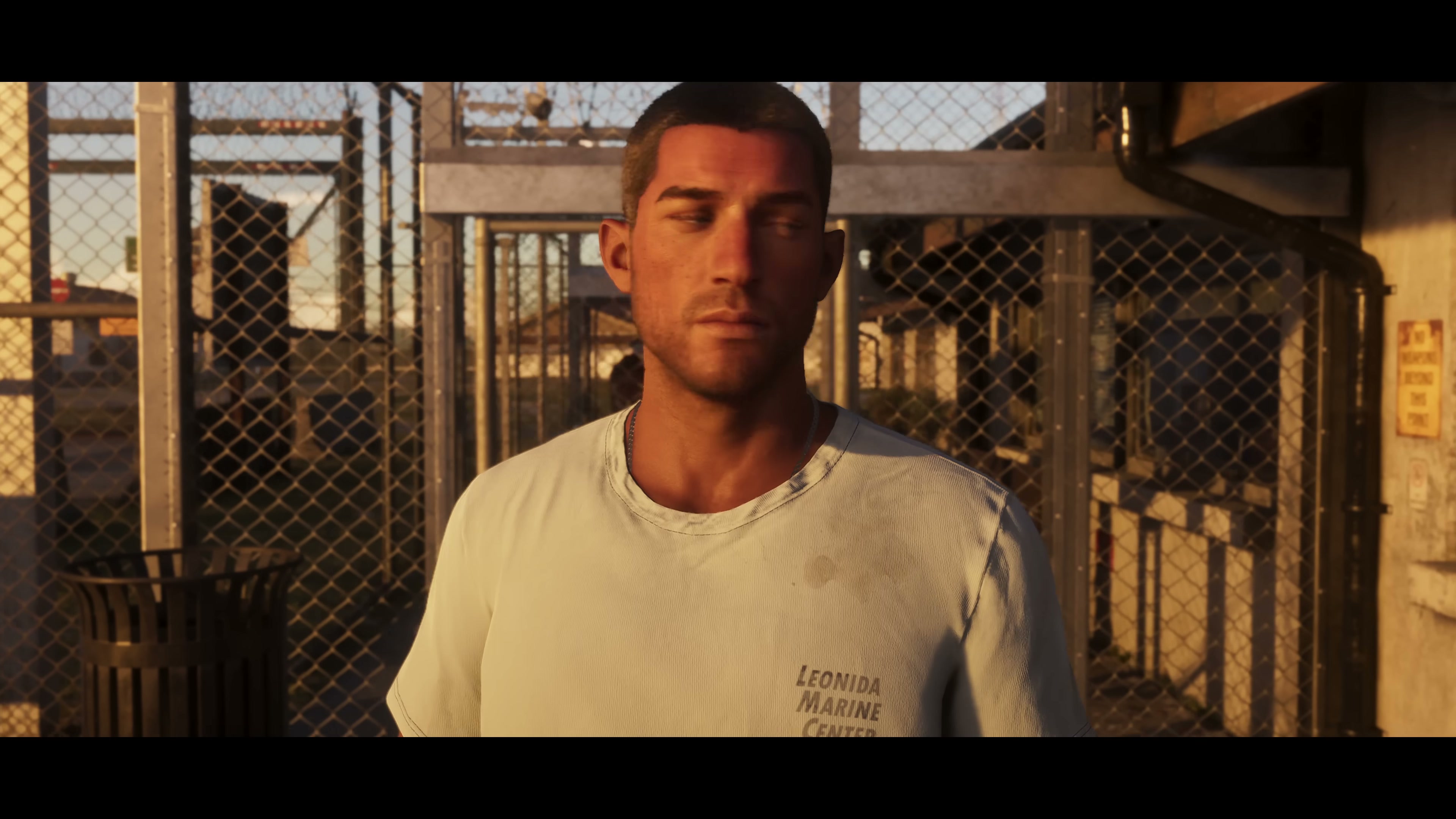 Jason in a 'Leonida Marine Center' t-shirt at golden hour behind chain-link fence
