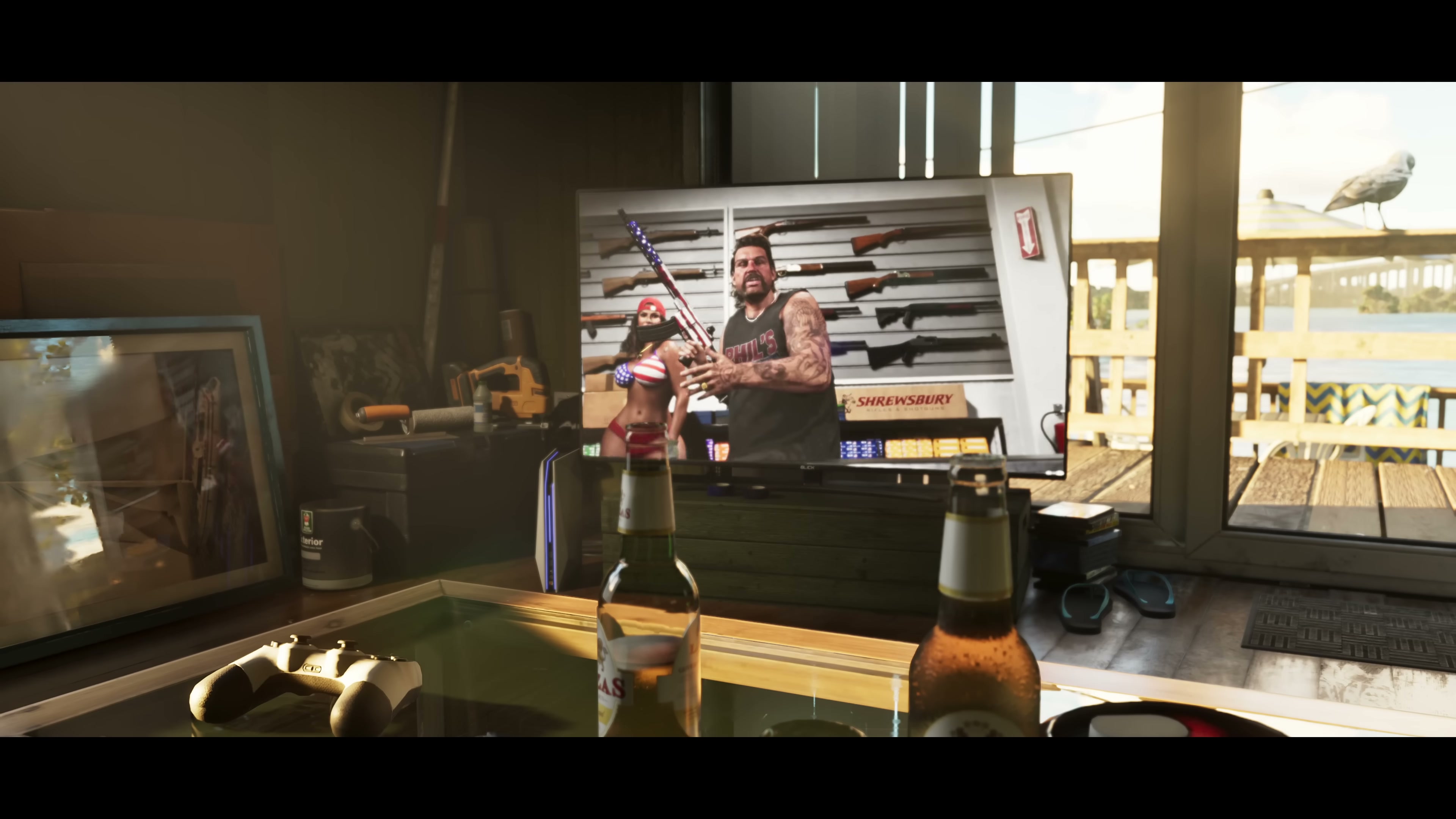 A television interior shows a tattooed man with a rifle in front of a wall of firearms; a game controller and beer bottles sit on a glass table in the foreground.
